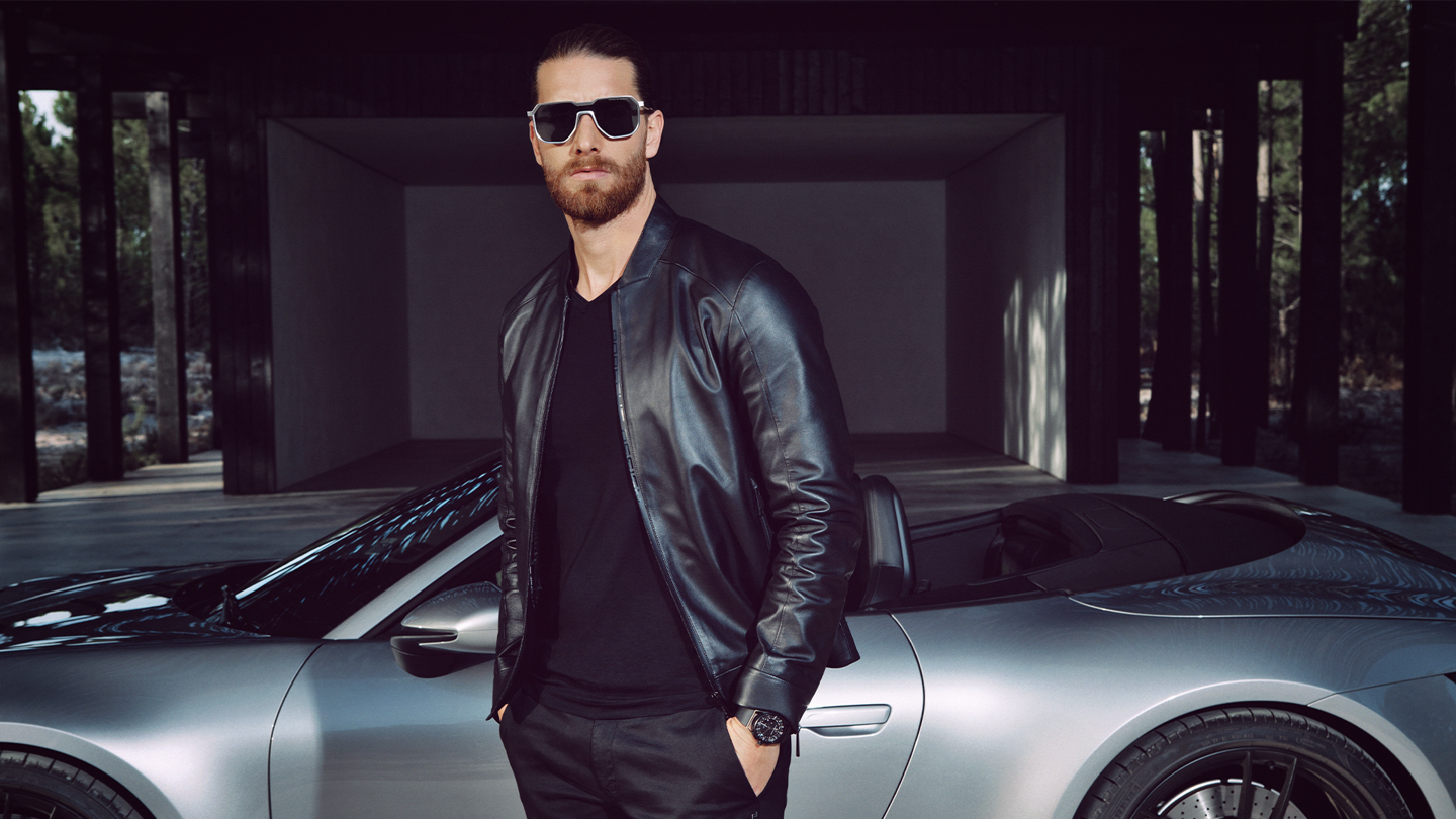 Shows Picture of Man_infront_silver_Porsche_with_sunglasses.png