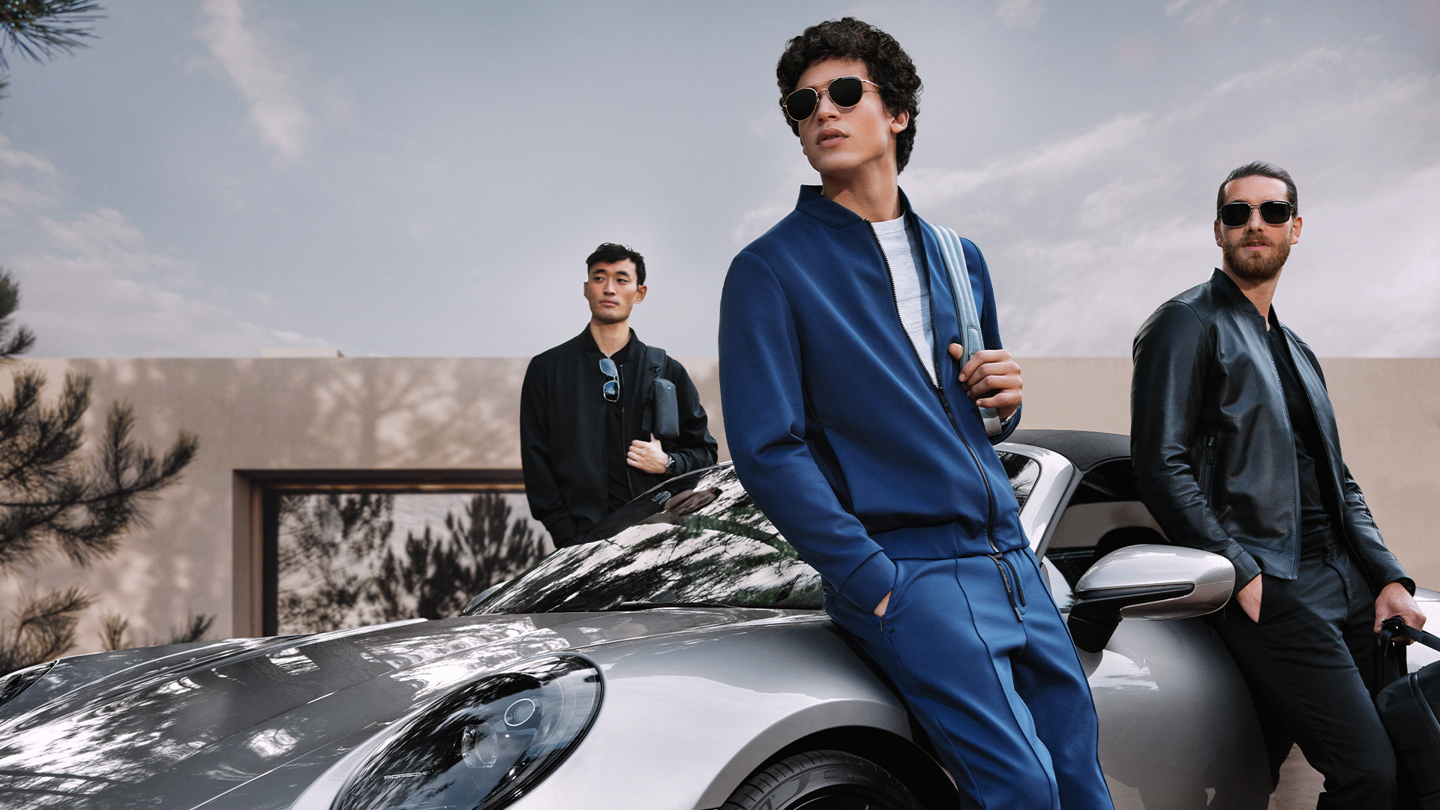 Shows Picture of man-leaning-against-silver-porsche-with-outfits-and-sunglasses.png