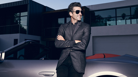 Patrick Dempsey standing in front of a Porsche